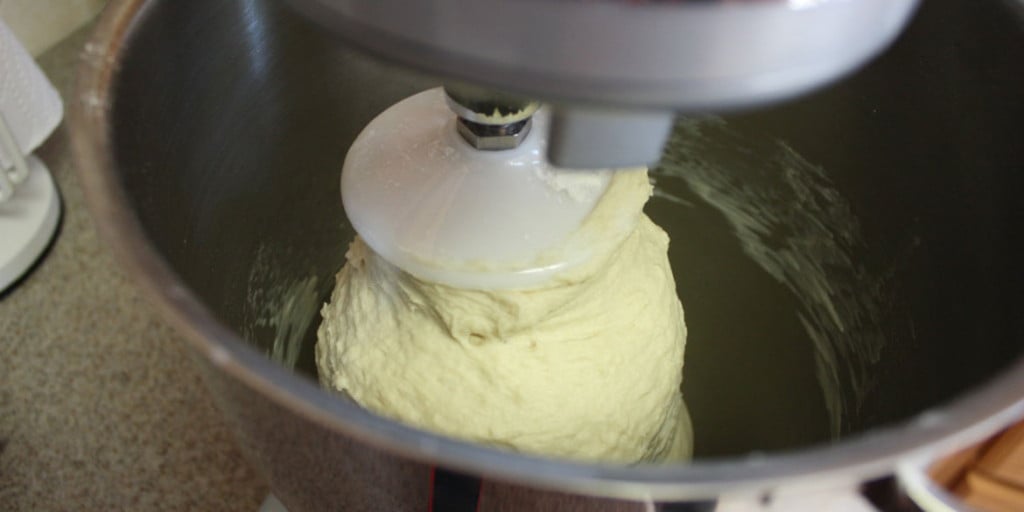 Sandwich bread dough on the dough hook of an electric mixer.