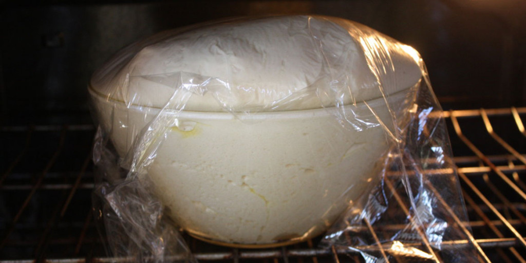 Bread dough risen over the glass bowl.