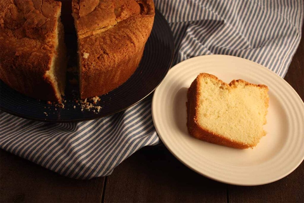 Sour cream pound cake with a slice on a white plate.