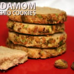 Cardamom pistachio cookies stacked on a red plate.