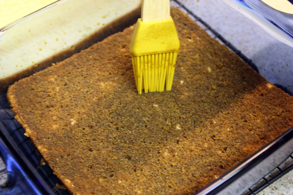 genoise cake being brushed with the espresso cognac mixture