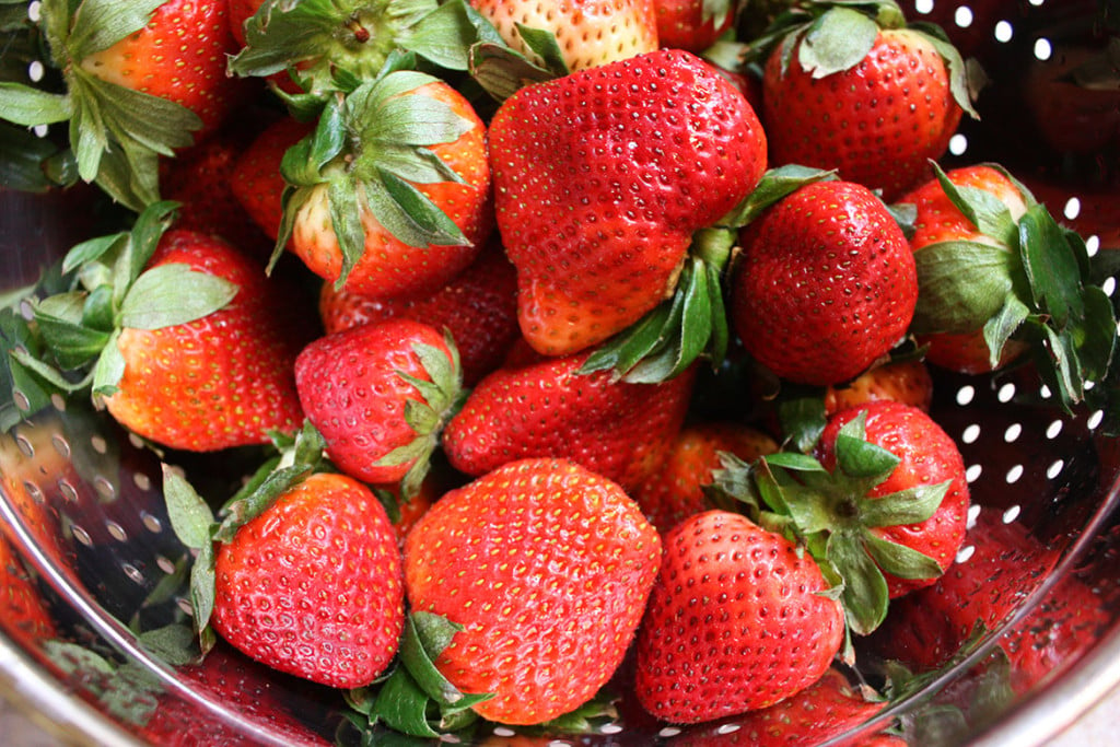 Fresh strawberries in a metal strainer.