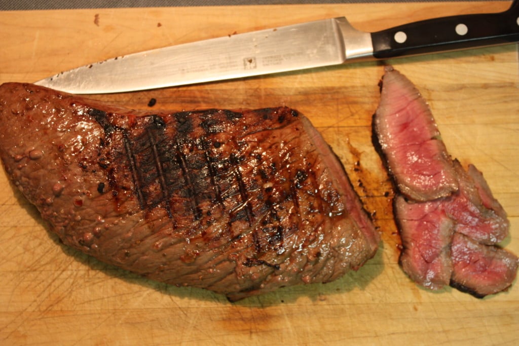 Sliced London Broil on a wooden cutting board.