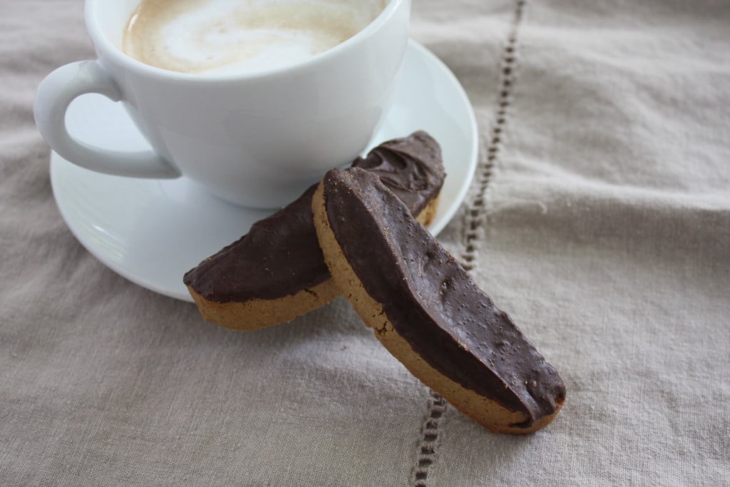 Espresso biscotti resting next to a latte.