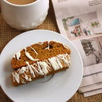 Pumpkin Spice Latte Biscotti - This biscotti on a white plate with coffee in the background..