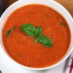 A bowl of tomato basil soup in a white bowl.