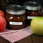 Slow cooker apple butter in mason jars surrounded by apples.