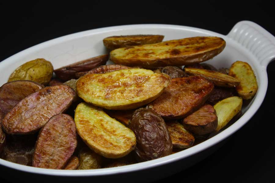 Roasted fingerling potatoes in a white serving dish.
