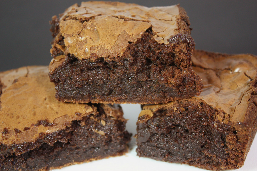 Perfect brownies stacked on a white plate.