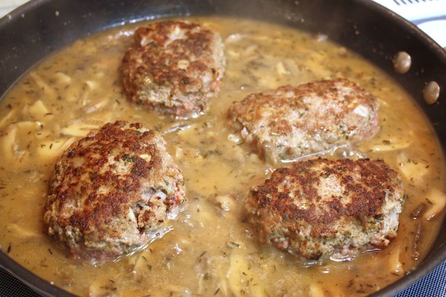 Salisbury patties in the skillet with the gravy ingredients.