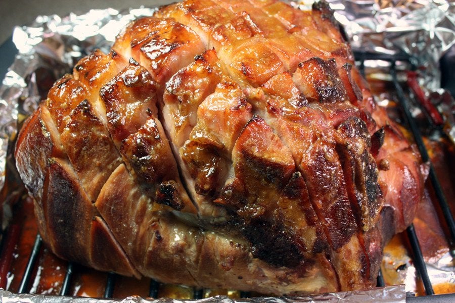 Brown sugar glazed ham in a foil lined roasting pan.