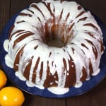 Meyer Lemon Bundt Cake on a cake dish with lemons around as a garnish.
