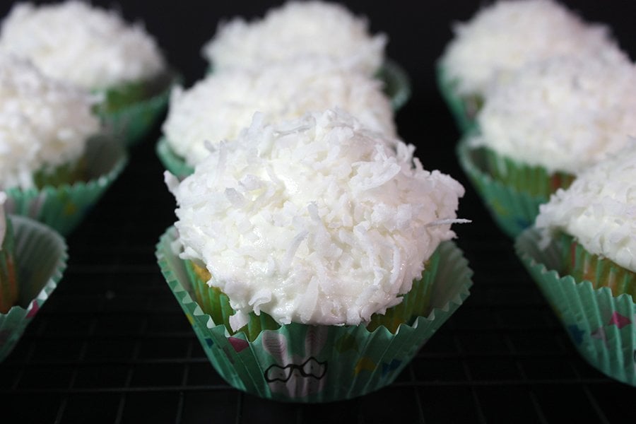 Coconut cupcakes lined up on a black background.