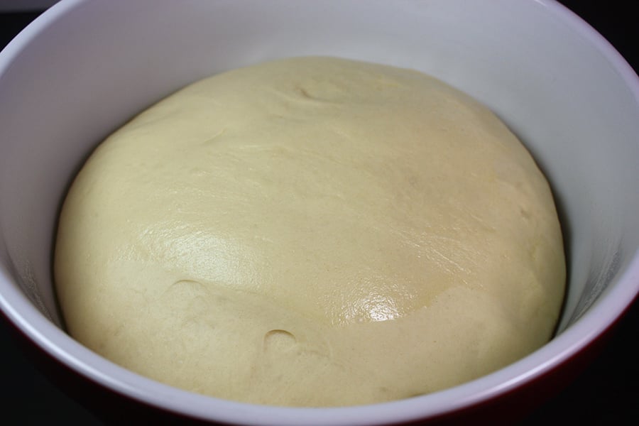 Bread dough risen in a red bowl.