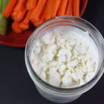 Blue Cheese Dressing in a mason jar with carrots and celery in the background.