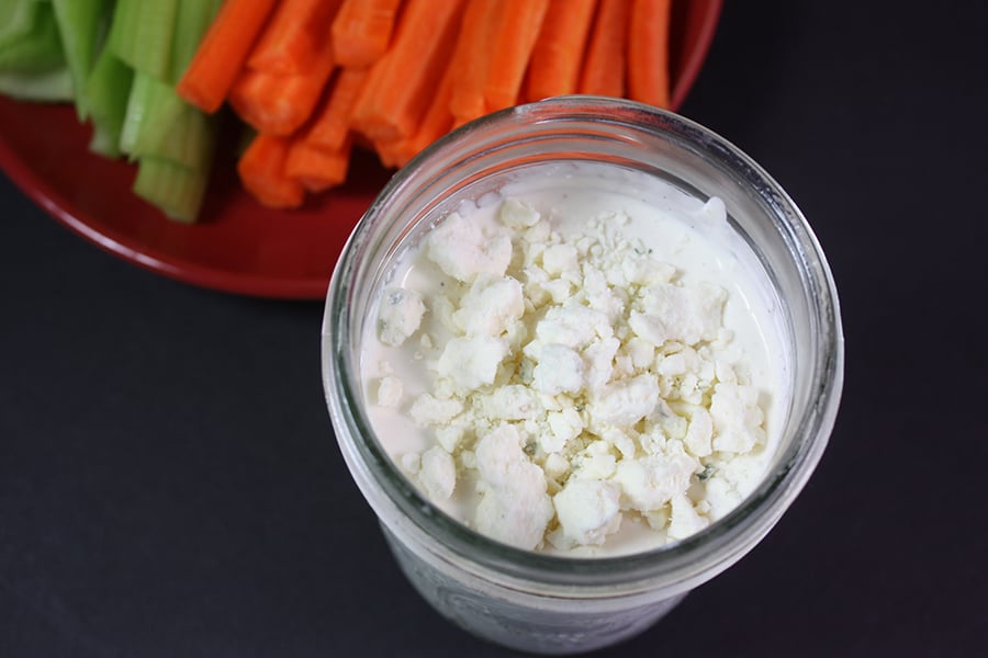 Blue Cheese Dressing in a mason jar with carrots and celery in the background.