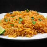 Mexican Rice with a cilantro and lime garnish on a white plate.