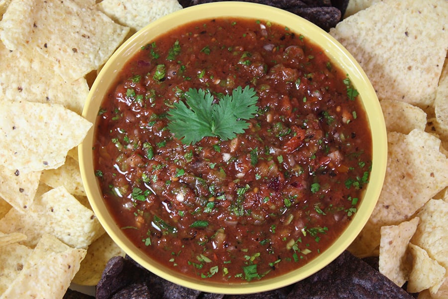 Fire roasted salsa in a bowl surrounded by tortilla chips.