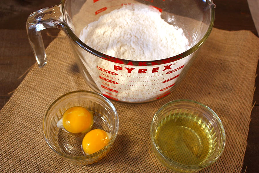 Flour in a glass bowl, egg yolks, and egg whites in separate ramekins.