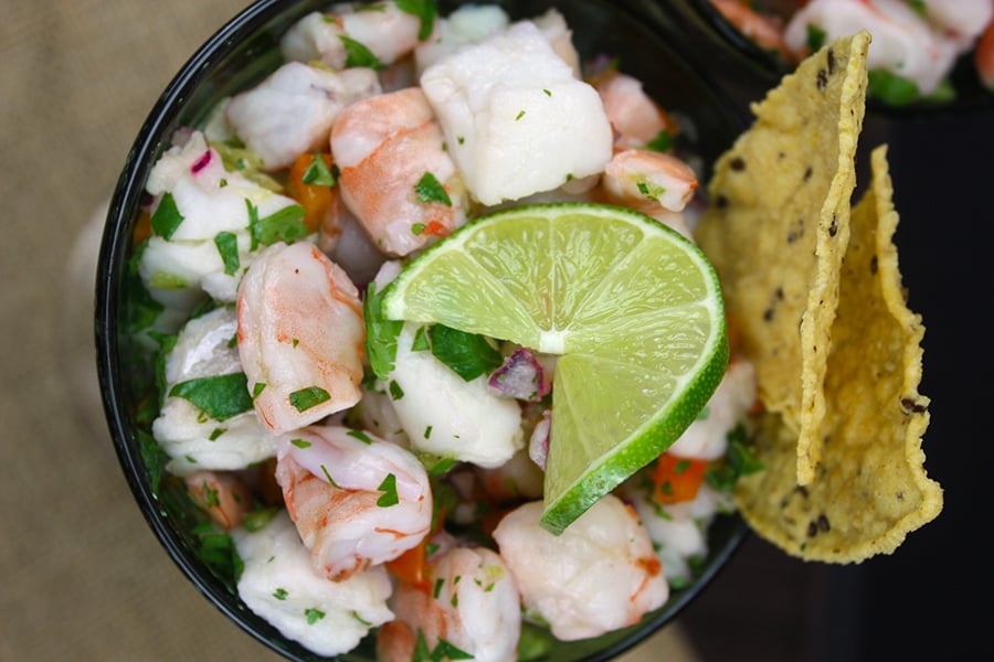 Ceviche in two green margarita glasses garnished with a lime slice and tortilla chips.