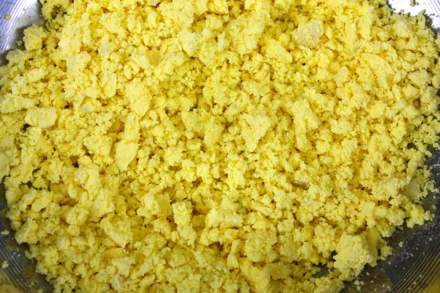 Smashed egg yolks in a metal mixing bowl.