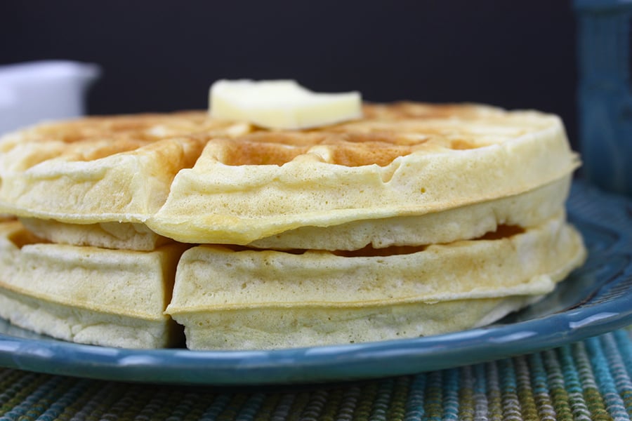 A stack of round waffles on a blue plate.