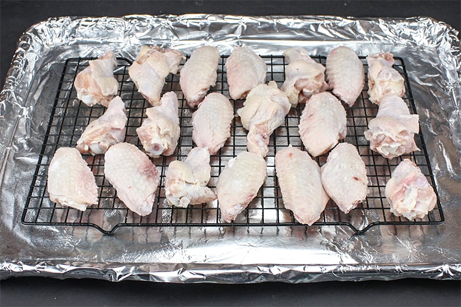 Chicken wings on a wire rack on a foil lined baking sheet.