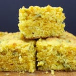 Jalapeno cornbread squares stacked on a cutting board.