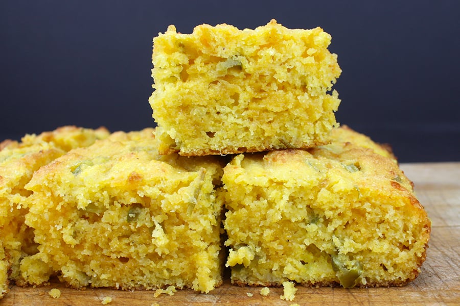 Jalapeno cornbread squares stacked on a cutting board.