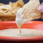 Dipping a chip into a restaurant style queso cheese dip.