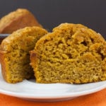 Bakery Style Pumpkin Muffin cut in half on a white plate.