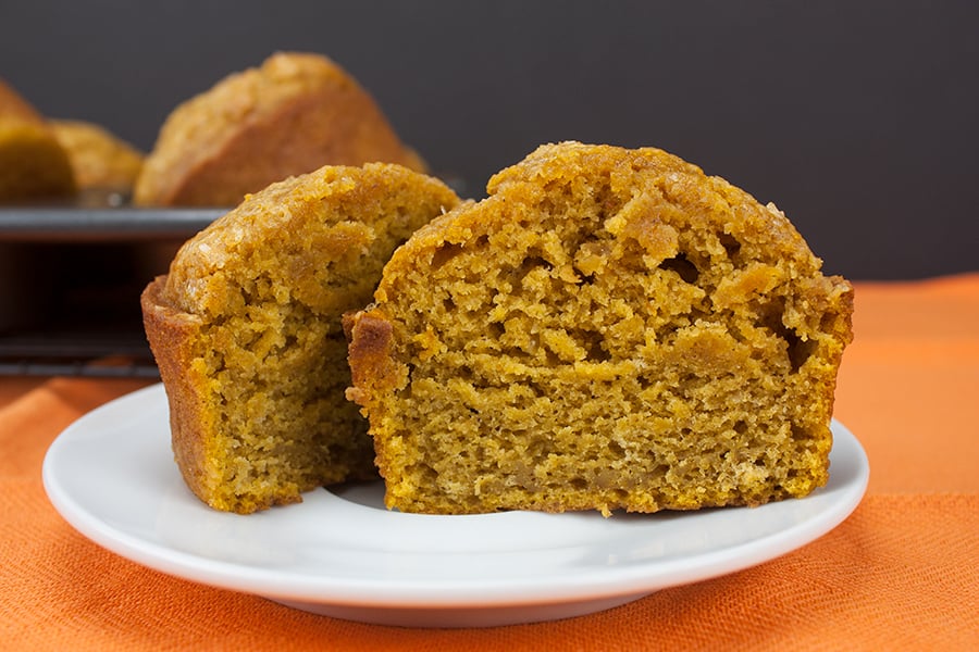 Bakery Style Pumpkin Muffin cut in half on a white plate.