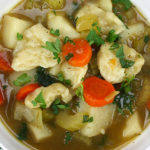 Vegetable dumpling soup in a white bowl.