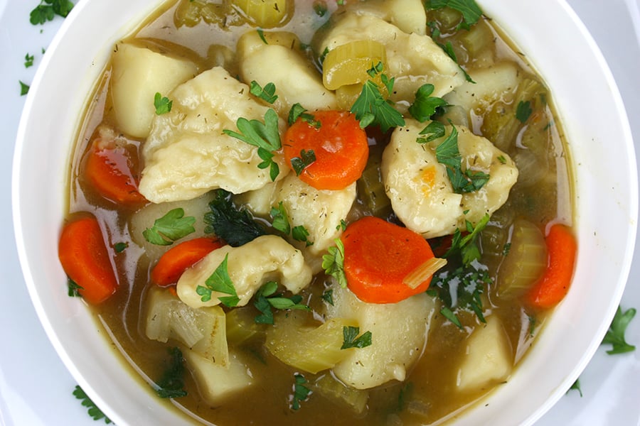Vegetable dumpling soup in a white bowl.