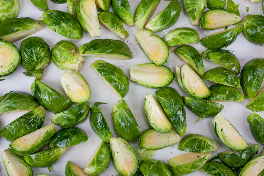 Raw brussels sprouts on a parchment lined baking sheet.