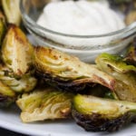 Roasted Brussel Sprouts with Aioli Dipping Sauce served on a white plate.