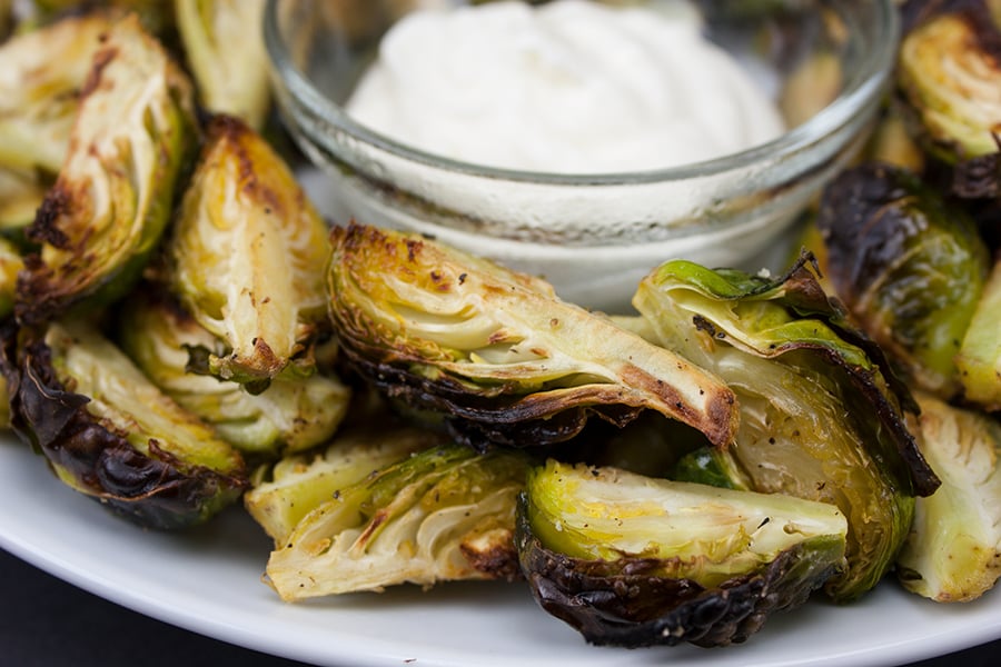 Roasted Brussel Sprouts with Aioli Dipping Sauce served on a white plate.