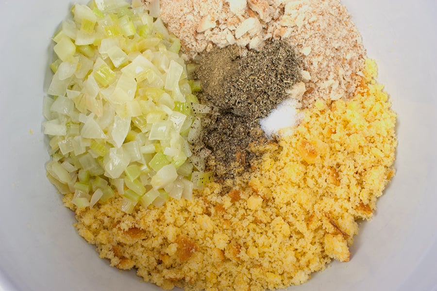 Crumbled cornbread, celery, onions, breadcrumbs, and seasonings in a mixing bowl.