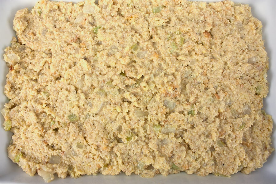 Unbaked southern cornbread dressing in a white casserole dish.