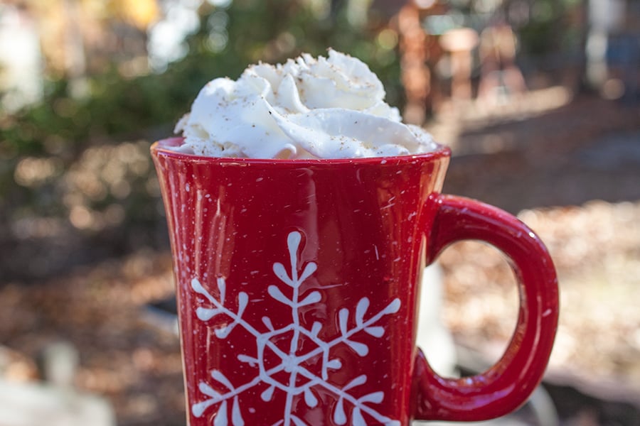 Eggnog latte in a red coffee mug with a snowflake design topped with whipped cream.