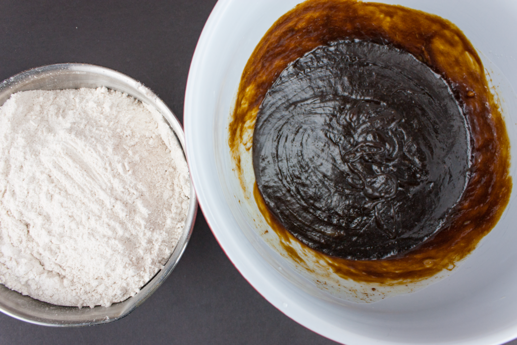 molasses cookie wet ingredients in a bowl next to dry ingredients in another bowl