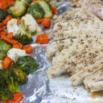 Sheet pan chicken and vegetables on a foil lined baking pan.