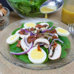 Spinach Salad with Curry Mustard Vinaigrette served on a glass plate.