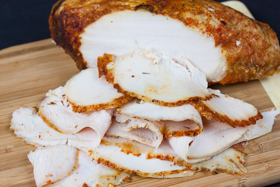 Homemade cajun turkey deli meat sliced on a wooden cutting board.