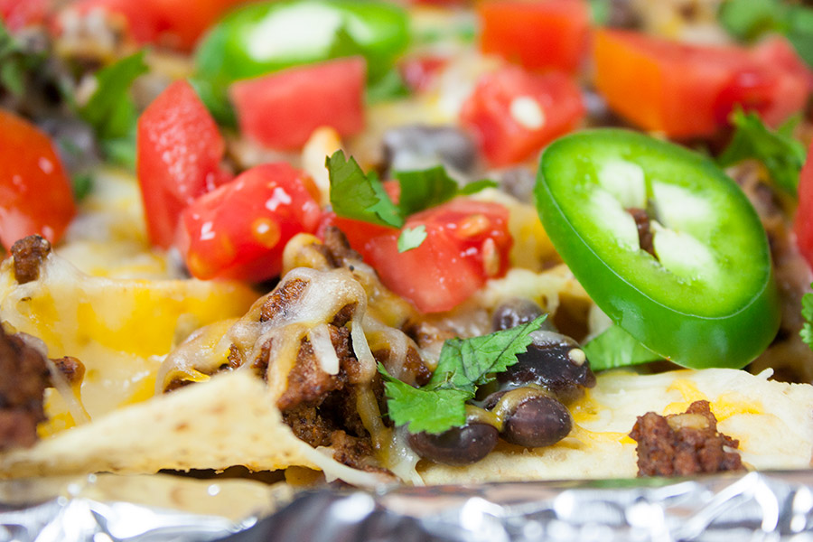 A closeup of a nacho with jalapenos and tomatoes