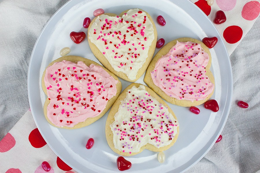 Soft frosted sugar cookies on a plate garnished with sprinkles.