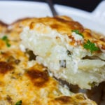 Creamy Herb Potatoes Gratin being served out of a white casserole dish.