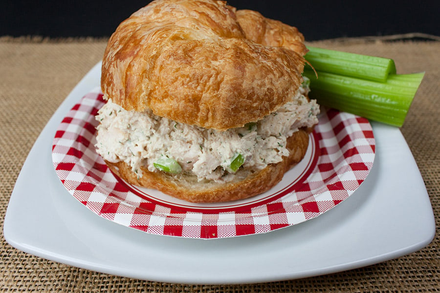 Savory Chicken Salad in a croissant on a white and red checked plate