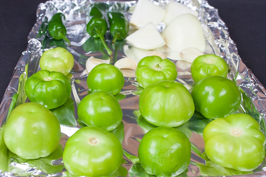 Homemade Roasted Tomatillo Salsa (salsa verde) - raw tomatillos, jalapenos, and onions on a foiled lined baking sheet