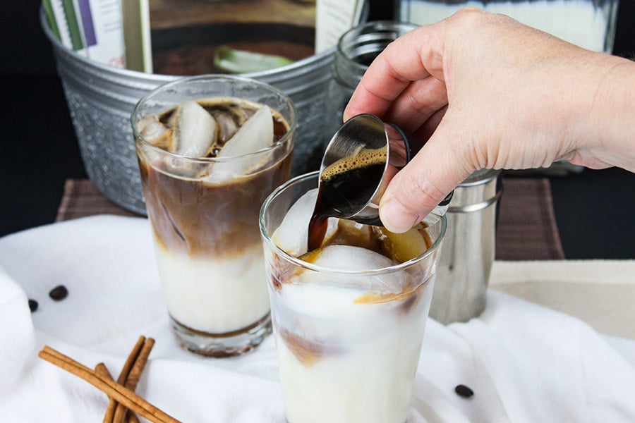 Iced Cinnamon Macchiato - espresso shots being poured over the milk in a clear glass